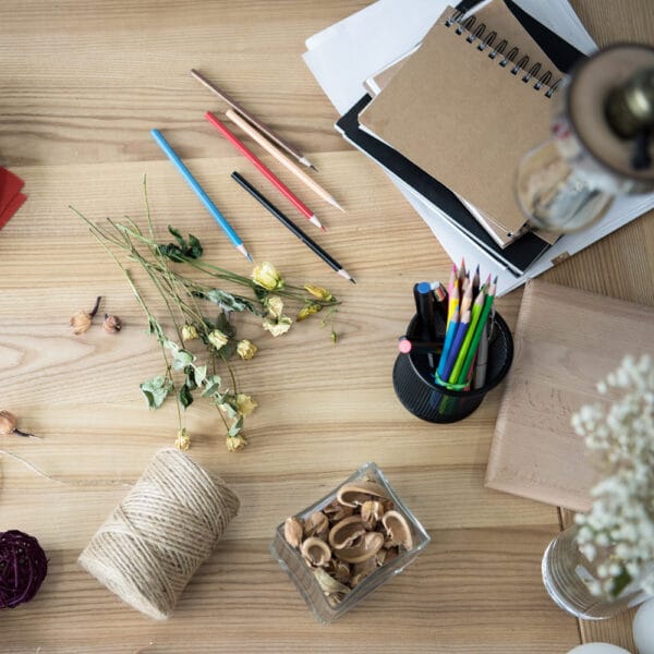 Table filled with natural art materials including dried flowers, pencils, and twine