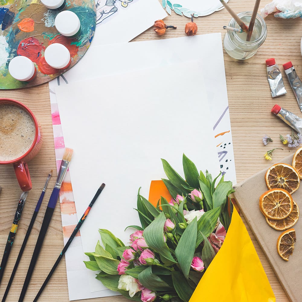About Us 3 Creative diy art workspace with coffee, dried flowers, brushes and paper at petal and still studio