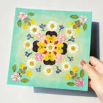 holding finished mandala artwork made with Serenity Light pressed flower kit – blooming with light and joy