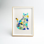 A framed artwork featuring a cat design created with pressed flowers, showcasing vibrant botanical colors.