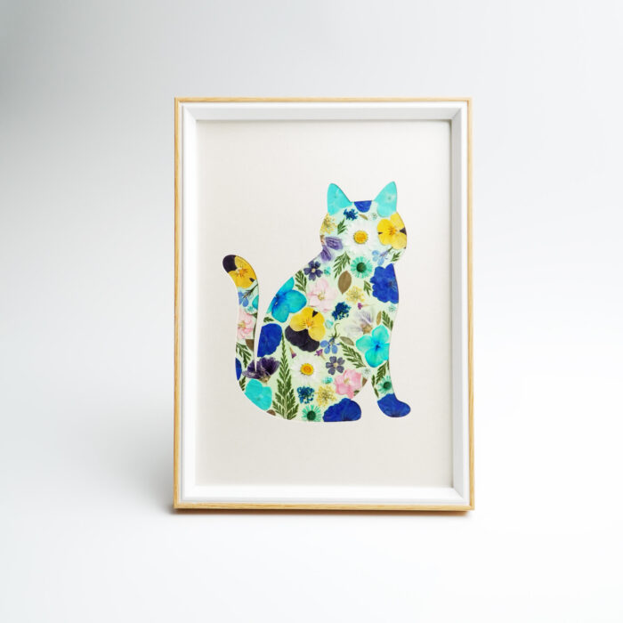 A framed artwork featuring a cat design created with pressed flowers, showcasing vibrant botanical colors.