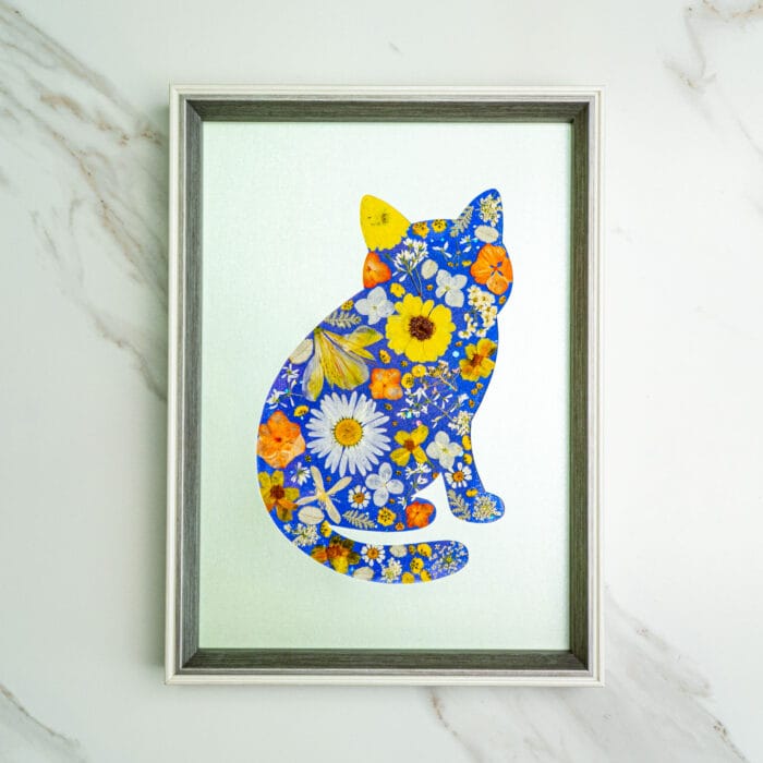 Pressed flower kit cat silhouette with vibrant blue background and daisy pressed flowers
