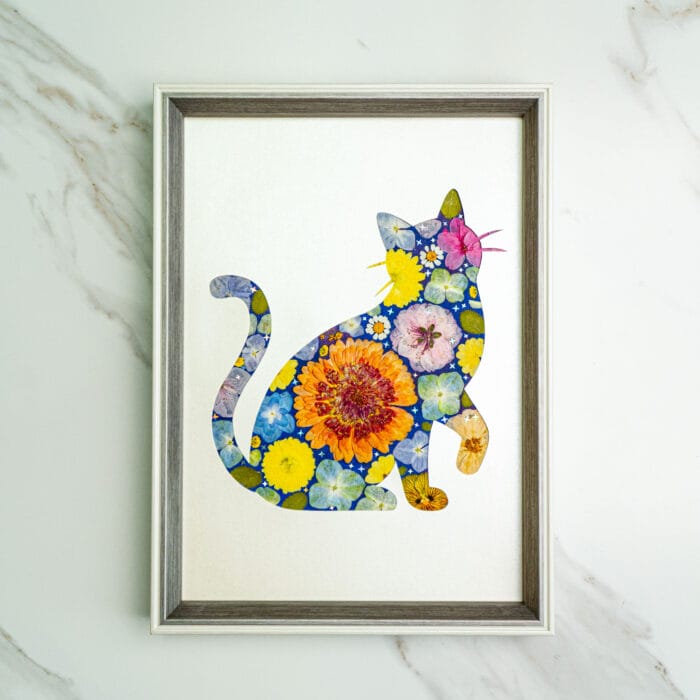 Pressed flower kit cat silhouette with blue background and orange, yellow, and pink flowers