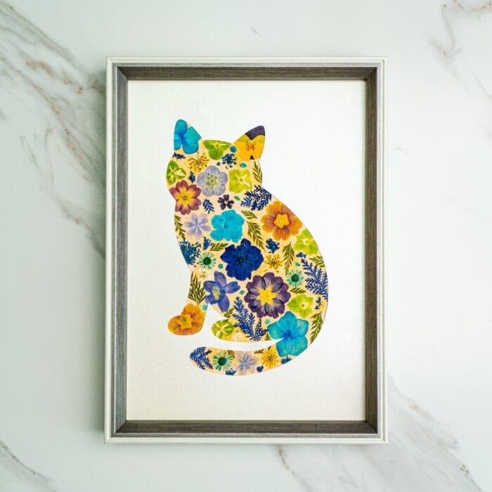 Pressed flower kit cat silhouette with blue, yellow, and orange flowers