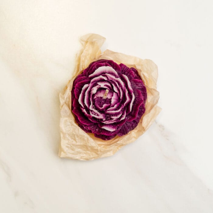 A handcrafted purple flower-shaped candle wrapped in kraft paper, included in the pressed flower kit as an ambient accessory.