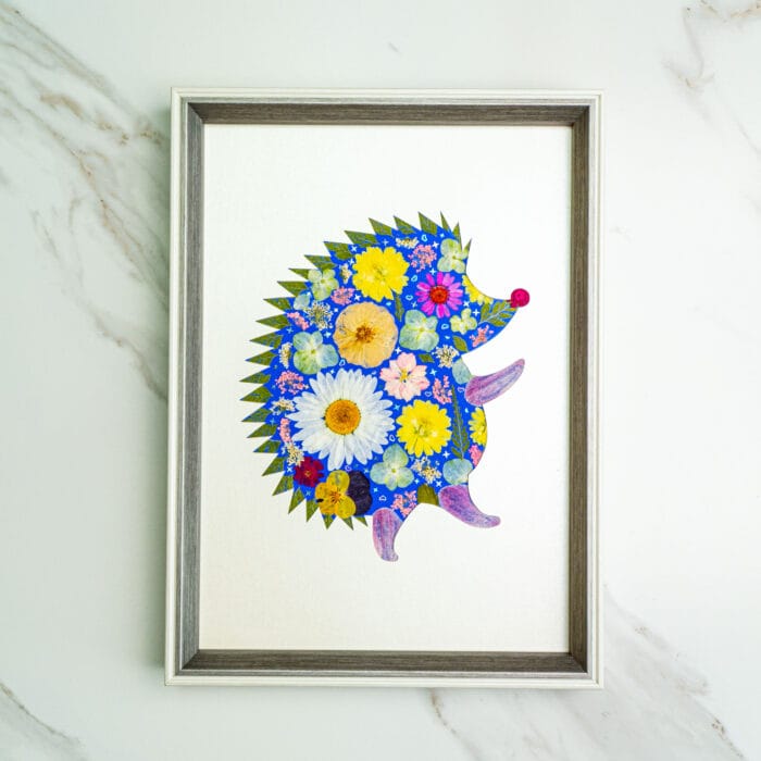 Pressed flower kit hedgehog silhouette with blue background and yellow, white, and pink flowers