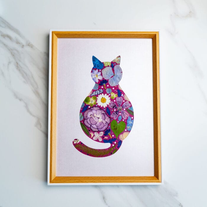 Pressed flower cat silhouette with vibrant purple and magenta florals on a soft lilac background.