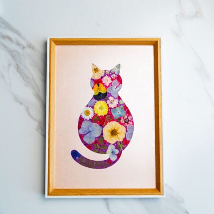 Bold pressed flower cat with vibrant red, yellow, and purple blossoms on a glowing rose-gold background.