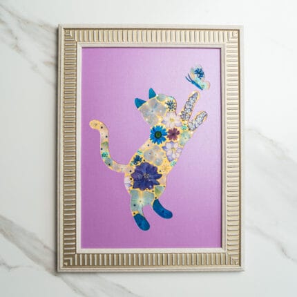 Pressed flower art of a playful cat silhouette decorated with blue and yellow flowers, reaching for a butterfly on a purple background