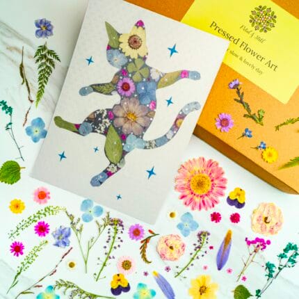 Pressed flower cat artwork of a dancing cat surrounded by stars, handmade collage with colorful pressed flowers