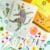 Pressed flower cat artwork of a dancing cat surrounded by stars, handmade collage with colorful pressed flowers