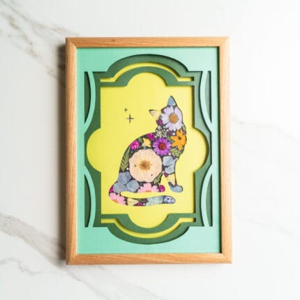 Pressed flower art of a sitting cat silhouette with colorful flowers, framed by layered green and yellow background