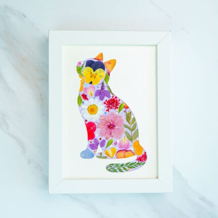 Pressed flower cat artwork full of vibrant purple, pink and yellow blooms, joyful handmade floral collage