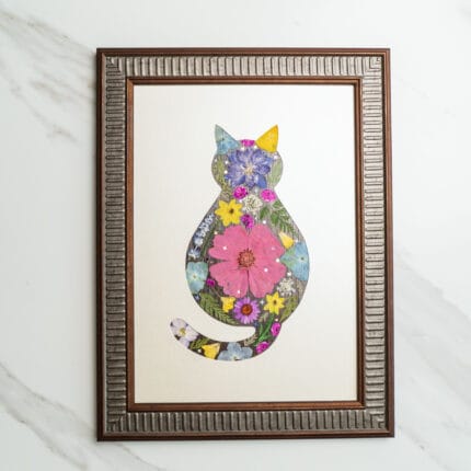 Pressed flower art of a cat silhouette with a large pink flower in the center, decorated with colorful blossoms