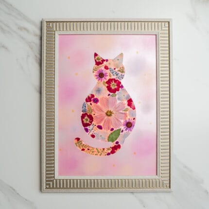 Pressed flower art of a cat silhouette filled with red and pink pressed flowers on a soft pink background