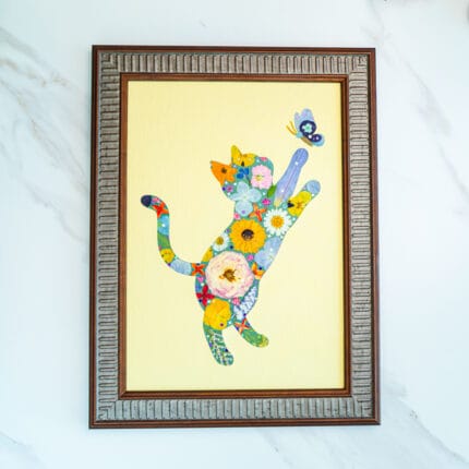 Pressed flower cat artwork of a playful cat reaching for a butterfly, handmade floral collage in frame