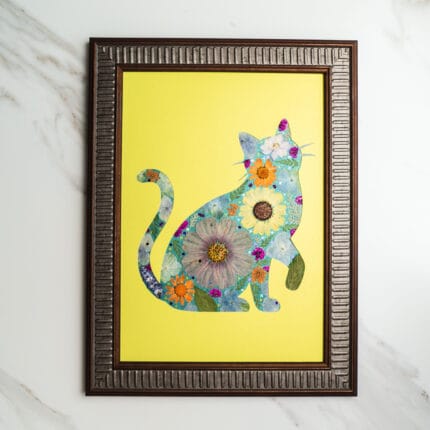 Pressed flower art of a cat silhouette with large pressed flowers in blue and orange on a bright yellow background