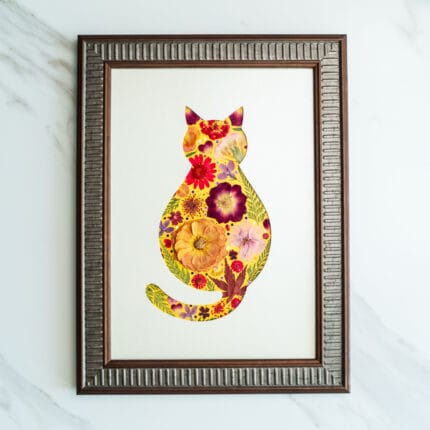 Pressed flower art of a cat silhouette with bright yellow and red flowers in a wooden frame