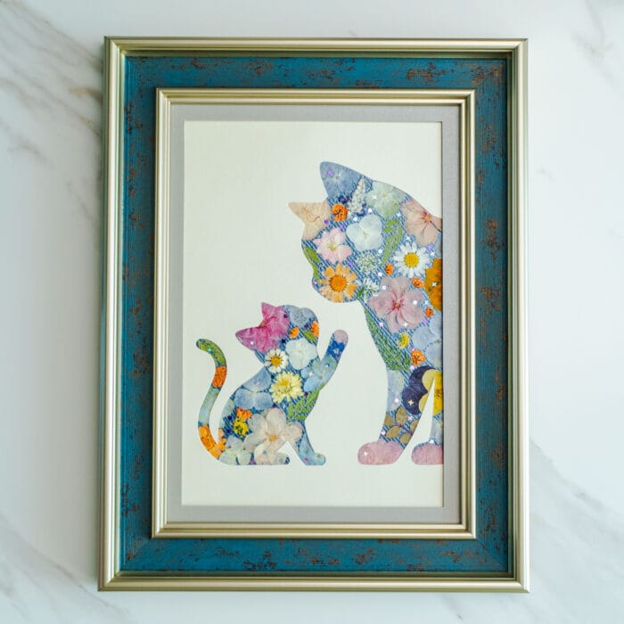 Pressed flower art of a mother cat and kitten silhouette decorated with pastel flowers in a blue frame