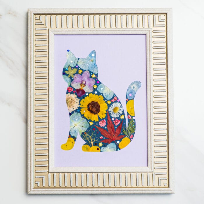 Pressed flower cat silhouette on lavender background, decorated with yellow, purple, and sunflower petals.