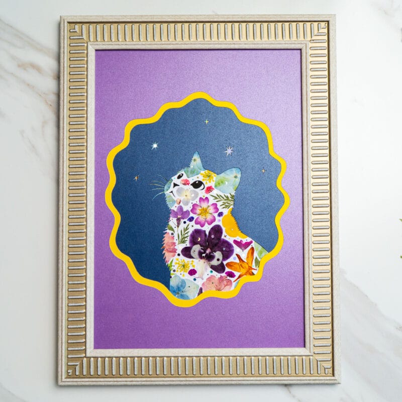 Pressed flower cat collage on purple frame, with night sky details and colorful floral arrangement.