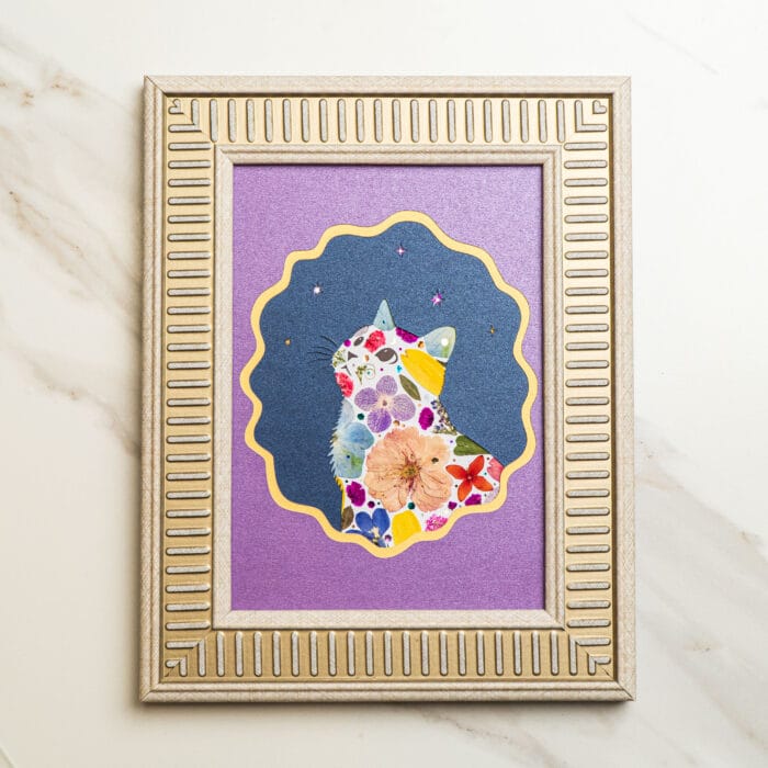 Pressed flower kit cat artwork “starry bloom” finished design with purple background and silver frame.